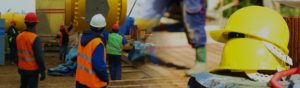 Workers in safety vests and hard hats work in manufacturing plant and construction site